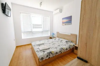 Double bed with folded towels, wall-mounted TV and air conditioner