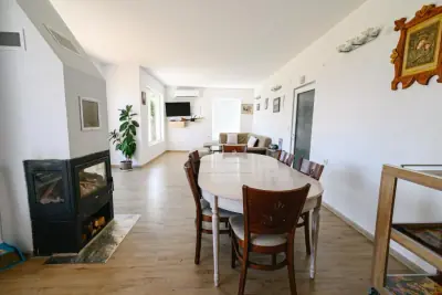 Open-plan living and dining with oval table and wood-burning stove
