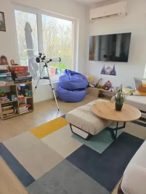 Living room with wall-mounted TV, beanbag, telescope and board games