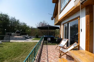 Tiled patio with wooden deck chairs, umbrella and sliding glass doors