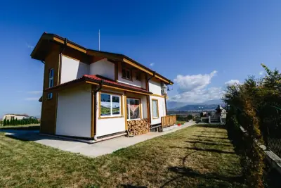 Two-story wooden chalet with stacked firewood and mountain views