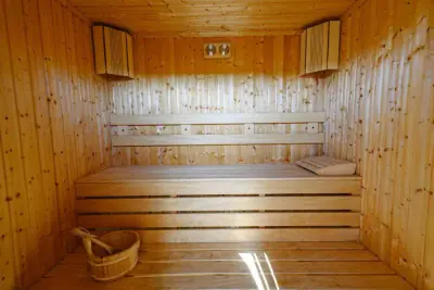 Wood-paneled sauna with slatted benches and wooden bucket