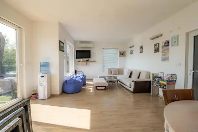 Open-plan living room with L-shaped sofa, wall-mounted TV and bean bag