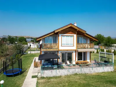 Front view of two-story villa with balcony and garden