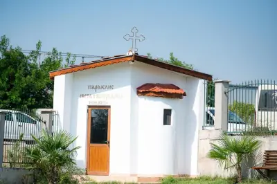 White chapel with red roof, cross and palm trees